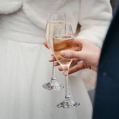 The couple hold two champagne flutes together.