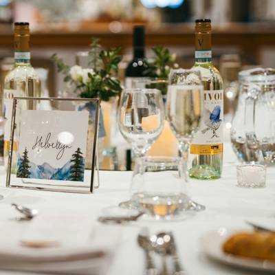 A framed table name card, Helvellyn, with wine bottles and glassware on the table.