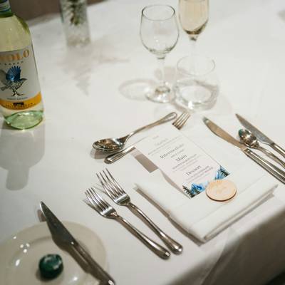 A printed menu on a folded napkin with a wooden tag at a place setting.