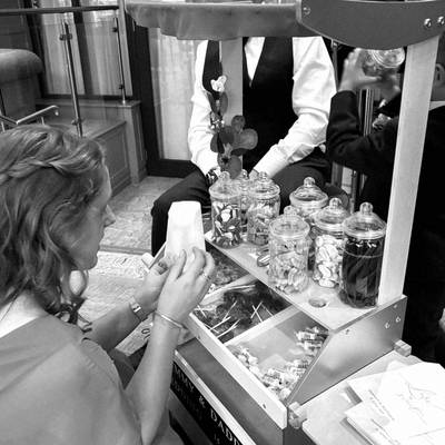A guest fills a paper bag at the sweet cart, black and white.