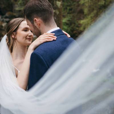The couple embrace beneath the flowing veil.