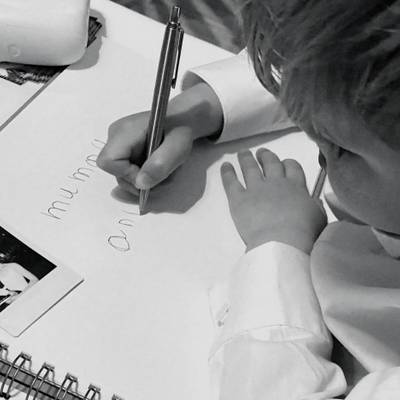 A young boy writes a message in the guestbook with a pen, black and white.